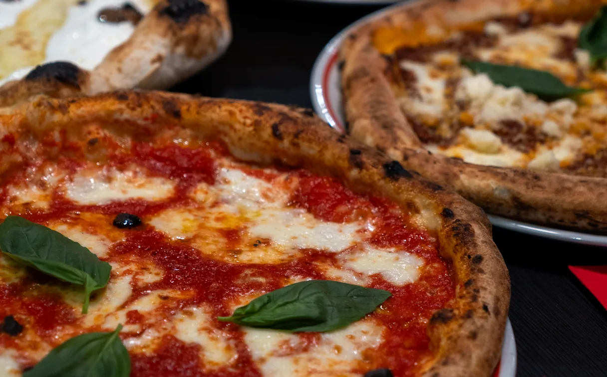 A margherita fresh from the oven, more pizzas behind it