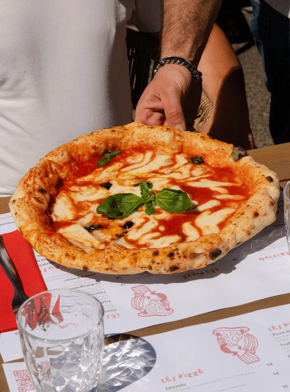 A margherita served on the Bella Ciao paper placemat printed with the menu and the drawings