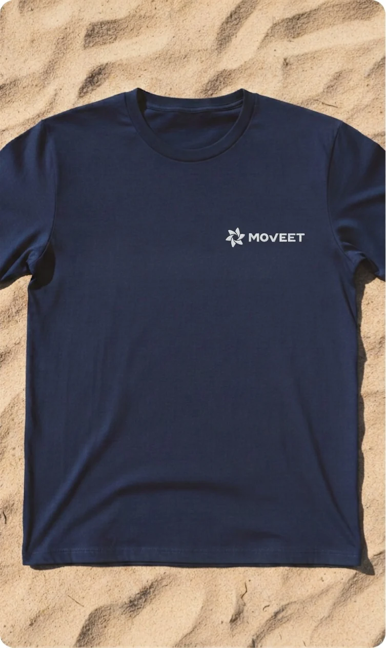 A deep blue T-shirt with the yellow Moveet lockup on the chest, lying on sand