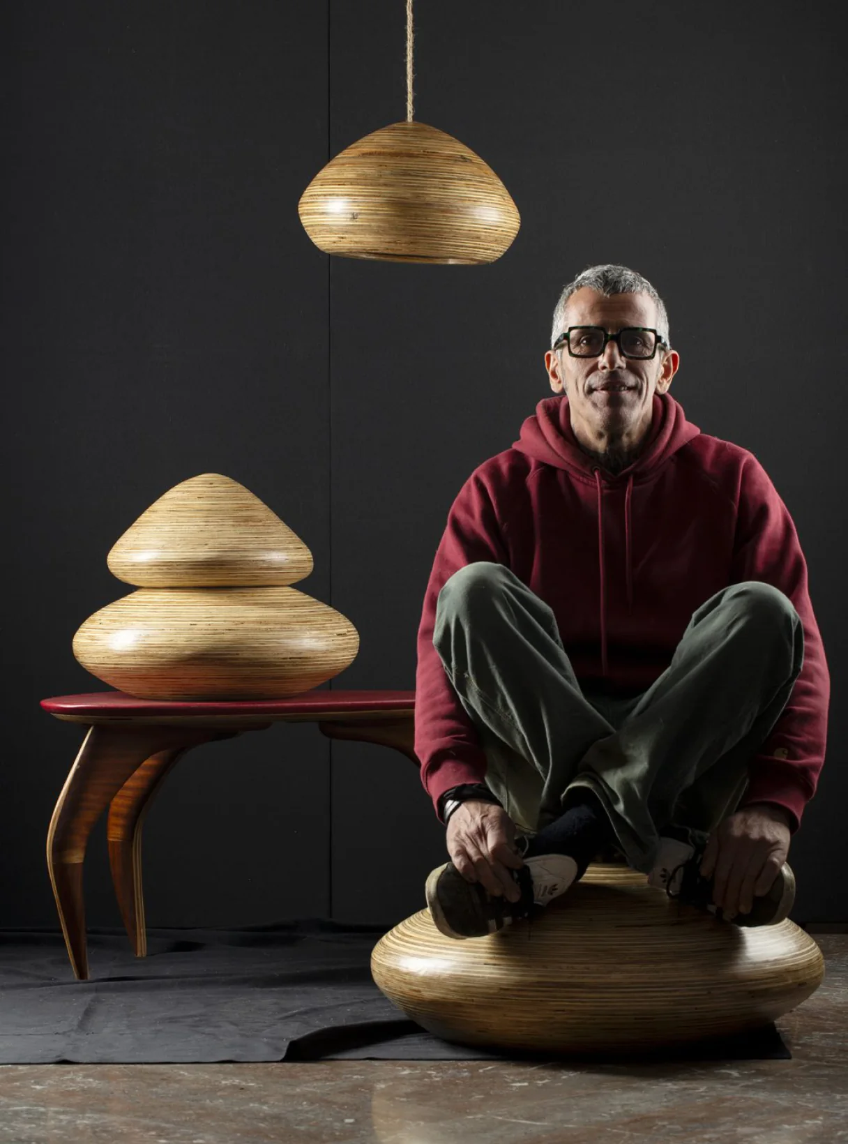 Salvatore Colantuono sitting in his workshop among his lamps